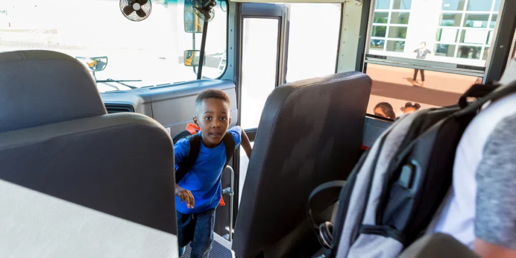 Young boy boarding the school bus with ridership technology